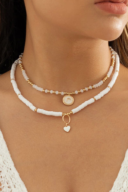 Layered boho necklace with white clay beads, gold accents, mother-of-pearl moon medallion and enamel heart