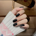 Hand wearing glossy black medium-length square press-on nails with high-shine finish