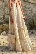 Model in a beige halter cross-front maxi dress with 3D floral texture and tiered ruffle hem
