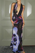 Woman in a printed sleeveless maxi dress with a draped halter neckline and slim fit