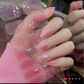 Medium-length pink ombré press-on nails with glitter and white butterfly accents on a hand