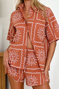 Model on a beach in a coral-and-green graphic-print long-sleeve shirt and matching shorts set