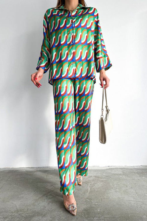 Model in retro geometric wave-print co-ord set in green, blue and orange, long-sleeve shirt and wide-leg pants